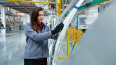 Female maintenance engineer examining car chassis.