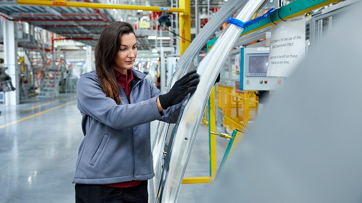 Female maintenance engineer examining car chassis.